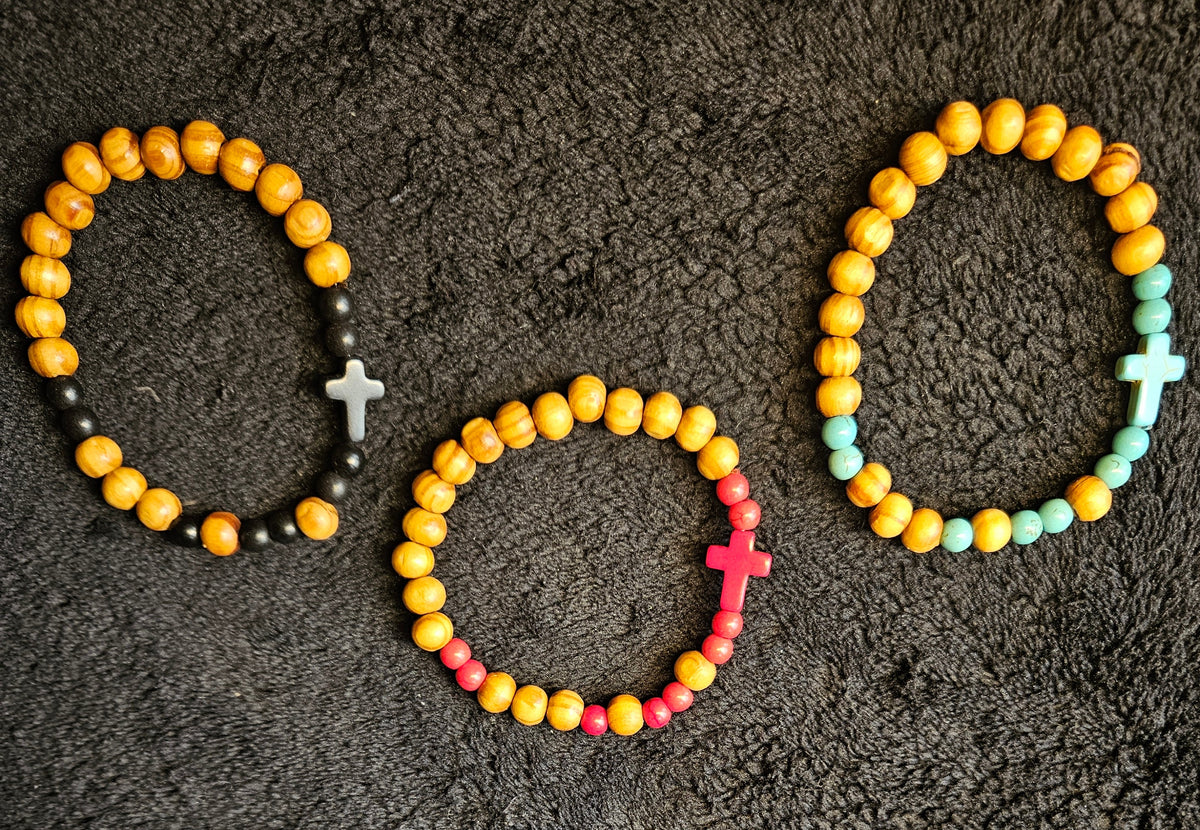Three beaded bracelets with colorful beads and metal clasps on a textured black surface.